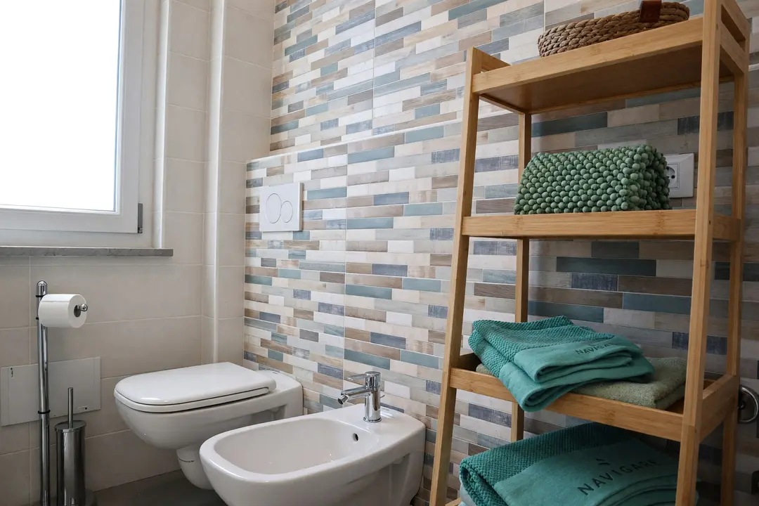 Il bagno dell’appartamento Ulivo, con le piastrelle colorate e gli asciugamani dedicati sulle mensole in legno