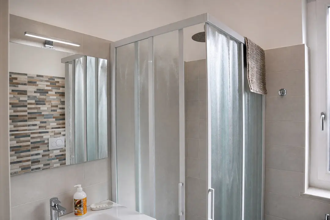 Il bagno dell’appartamento Limone: il box doccia con il soffione, lo specchio e il lavabo