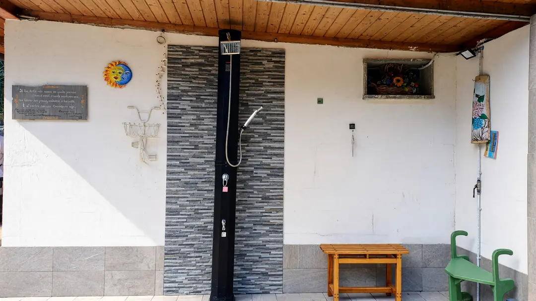 La doccia solare esterna sotto il portico, con lo sgabello di legno