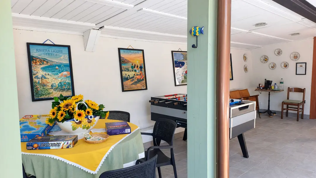 Il portico comune: il tavolo con i girasoli, il calciobalilla e i manifesti della Riviera alle pareti