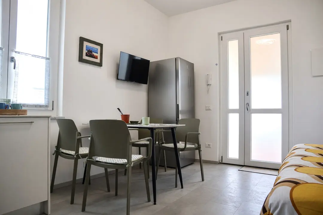 Il soggiorno dell’appartamento Ulivo: tavolo, sedie e la porta vetrata sul terrazzo