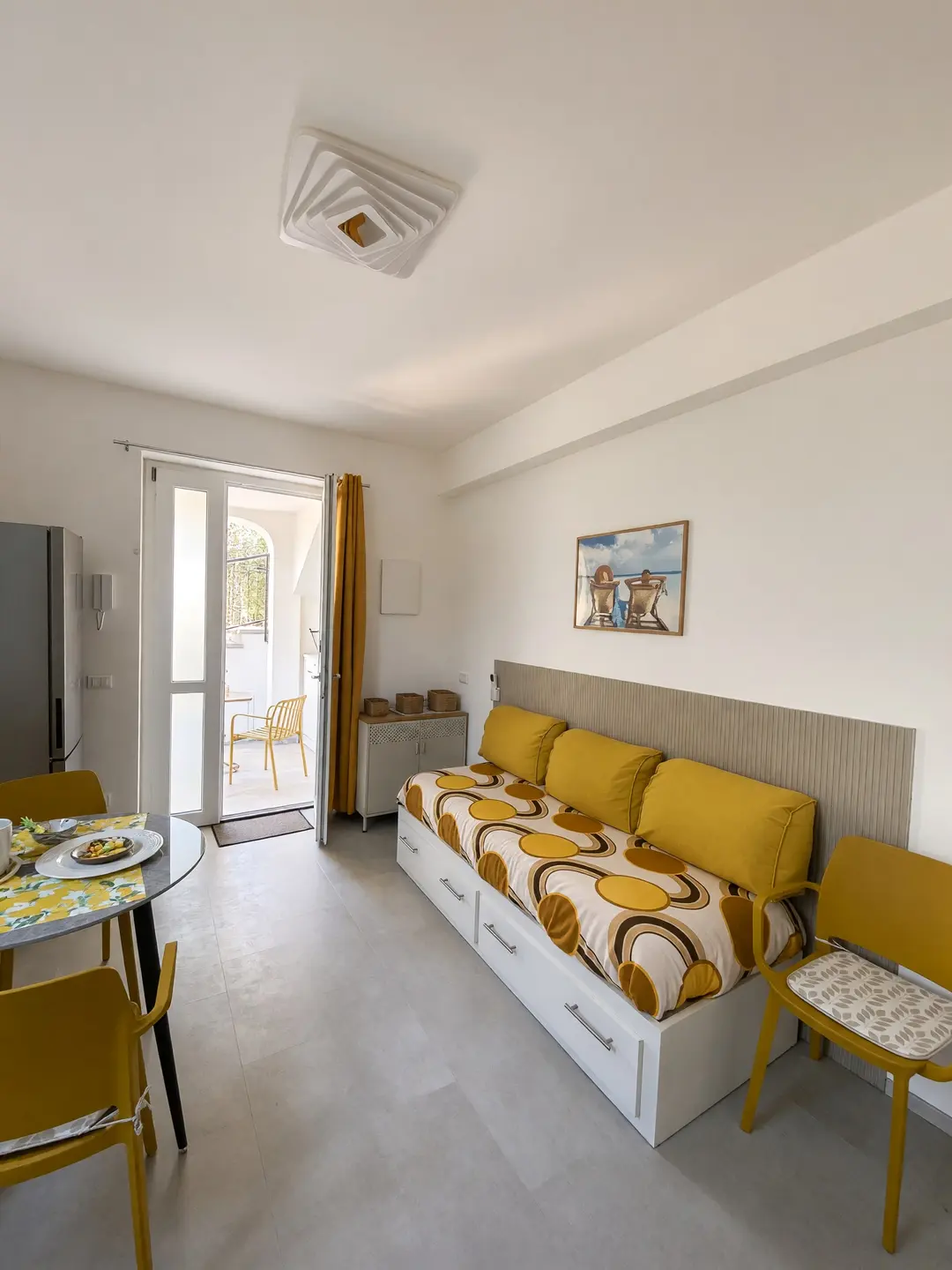 Il soggiorno dell’appartamento Limone, con il divano letto giallo e la porta sul portico